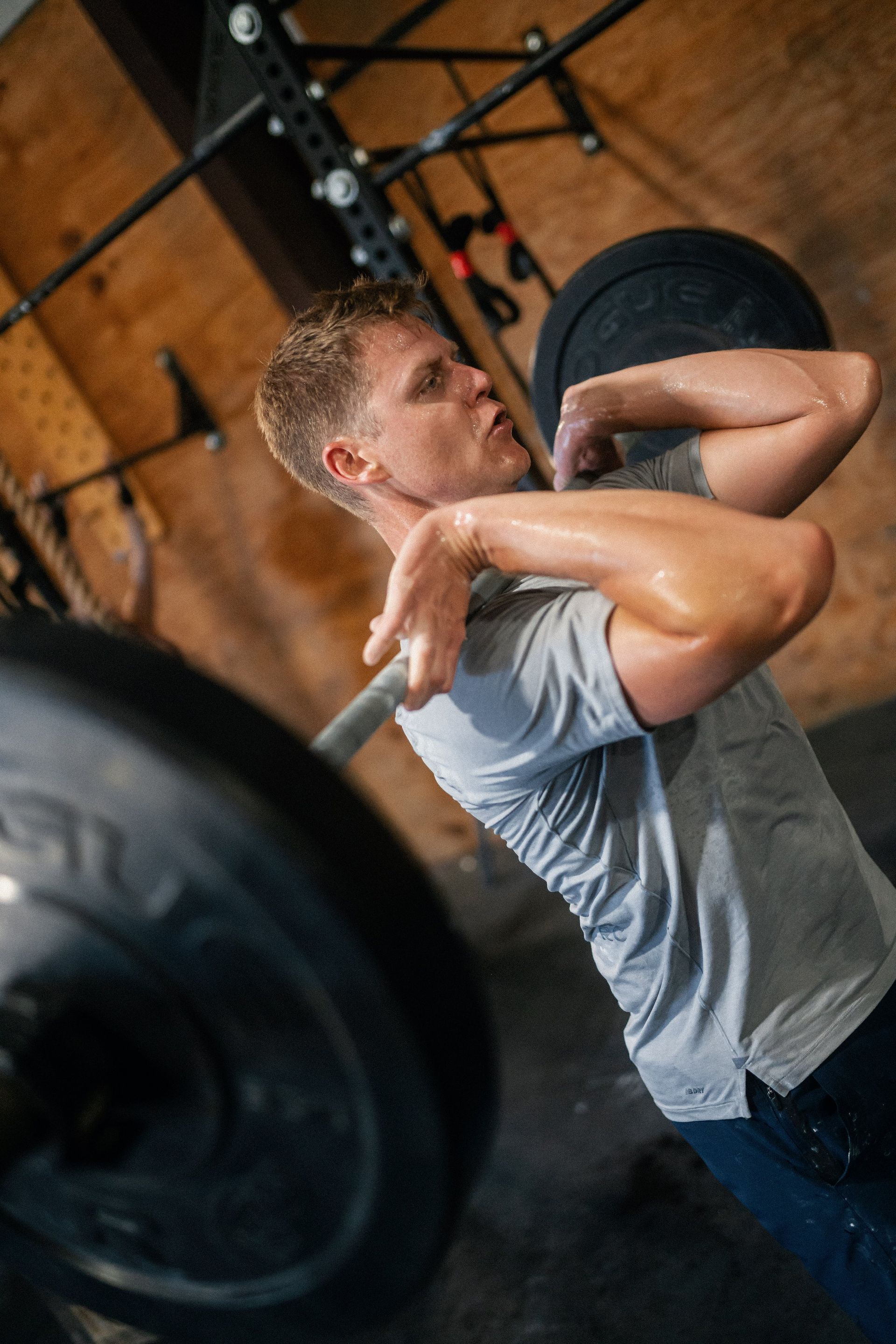 A man is lifting a barbell over his head in a gym.