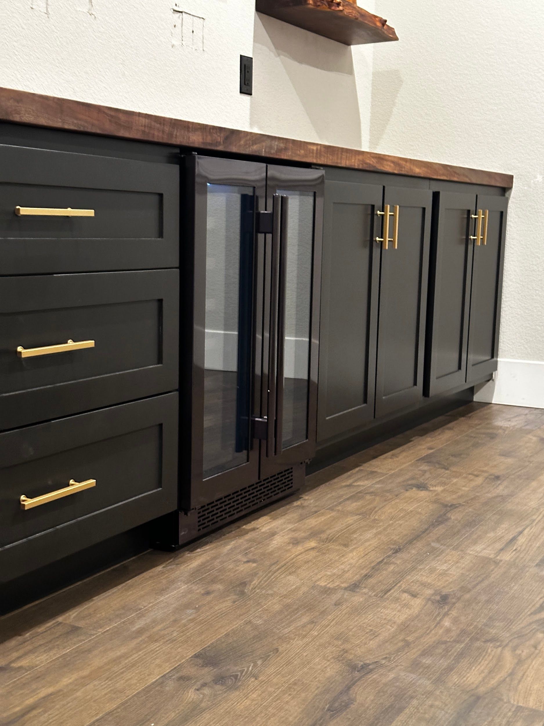 A kitchen with black cabinets and a wine cooler.