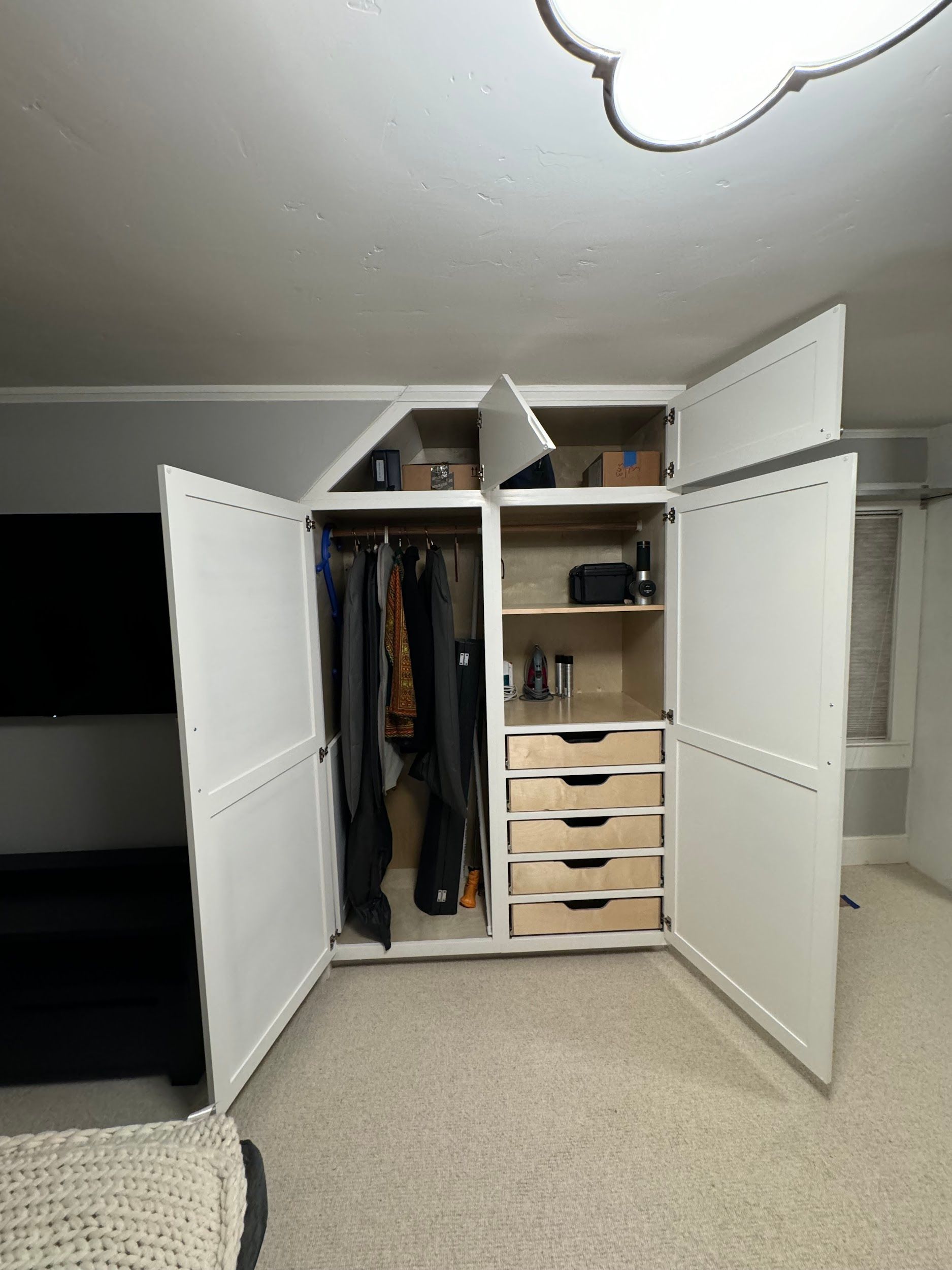 A large white closet with drawers and shelves in a living room.