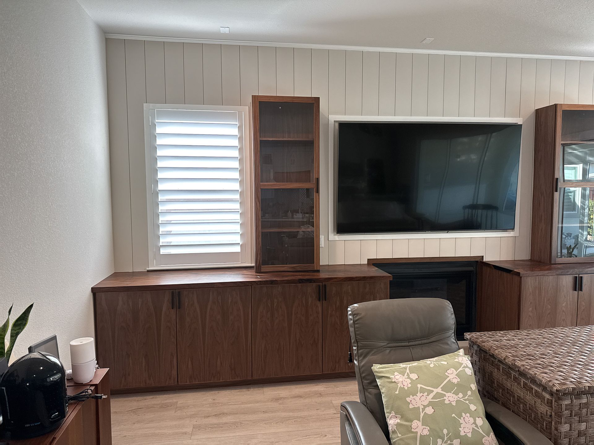 Living room with wood cabinets, a fireplace, TV, and a chair with a pillow.