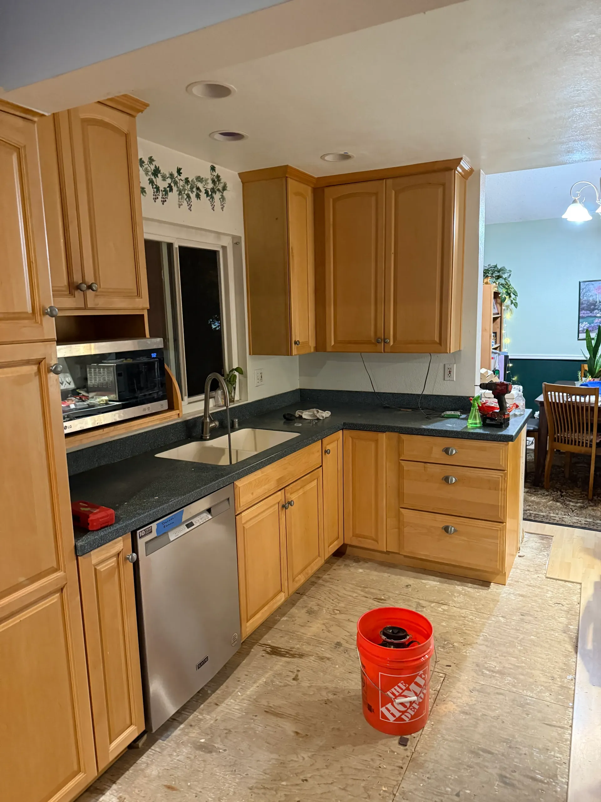 A kitchen with wooden cabinets and a red bucket on the floor