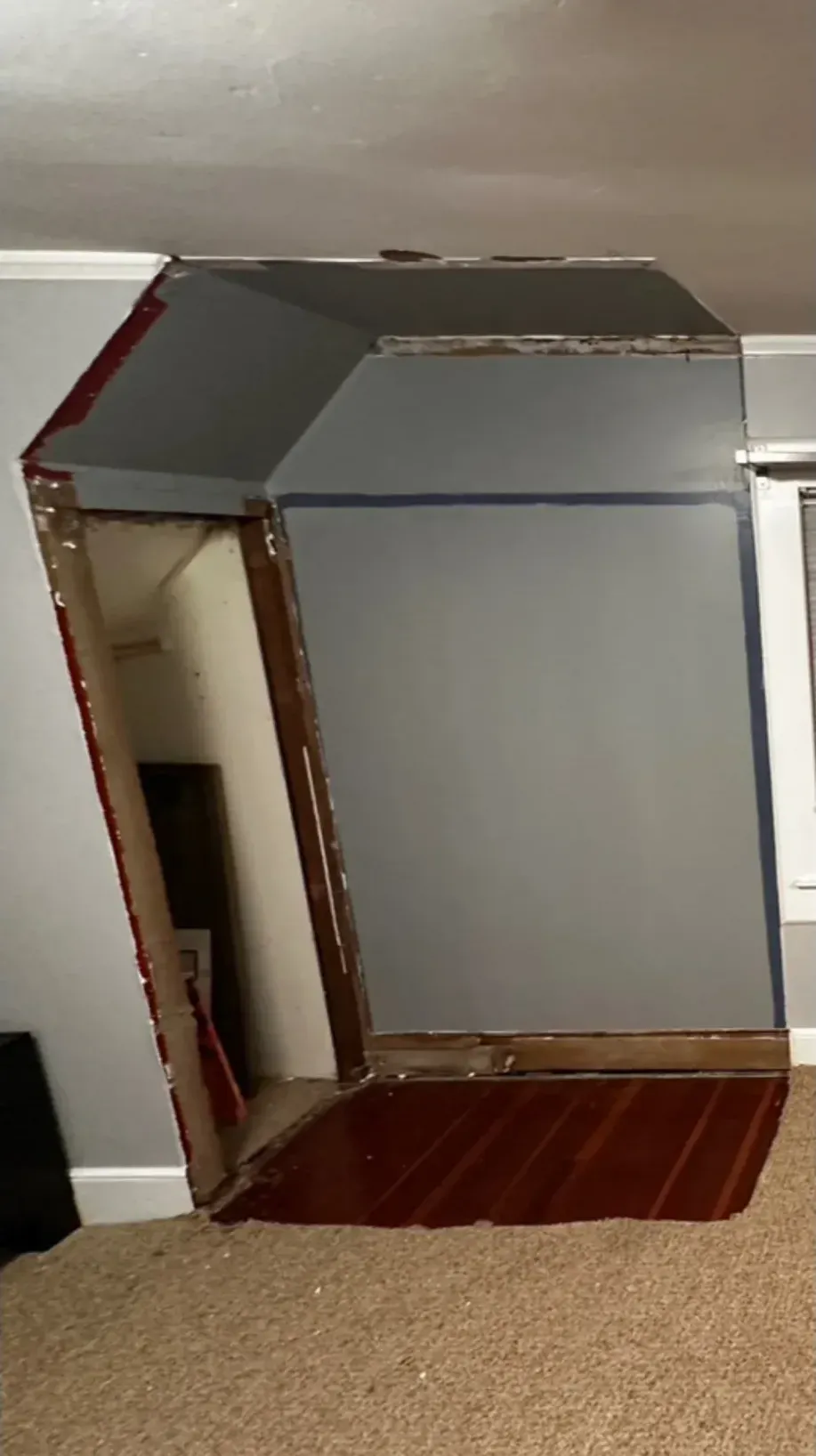 A gray box is sitting in a room next to a window.