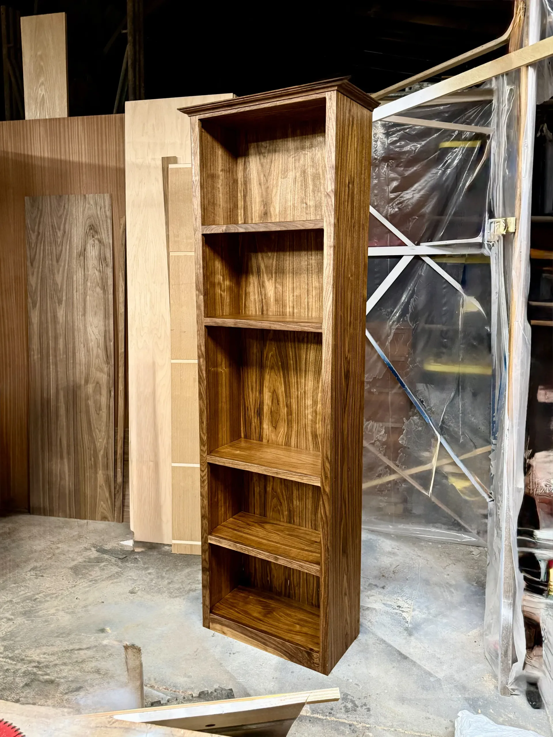 A wooden bookshelf is sitting in a warehouse.