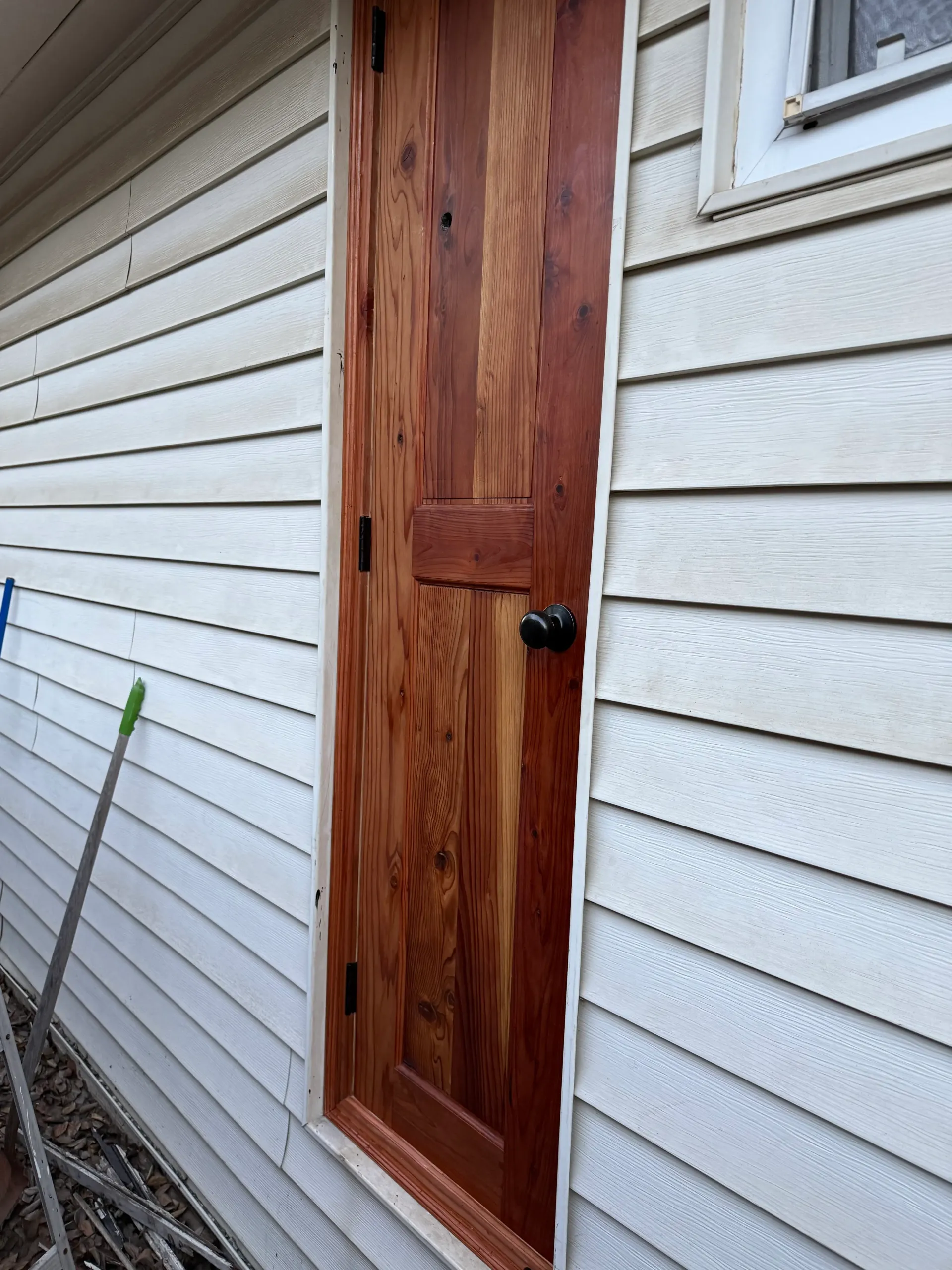 A wooden door is on the side of a white house.