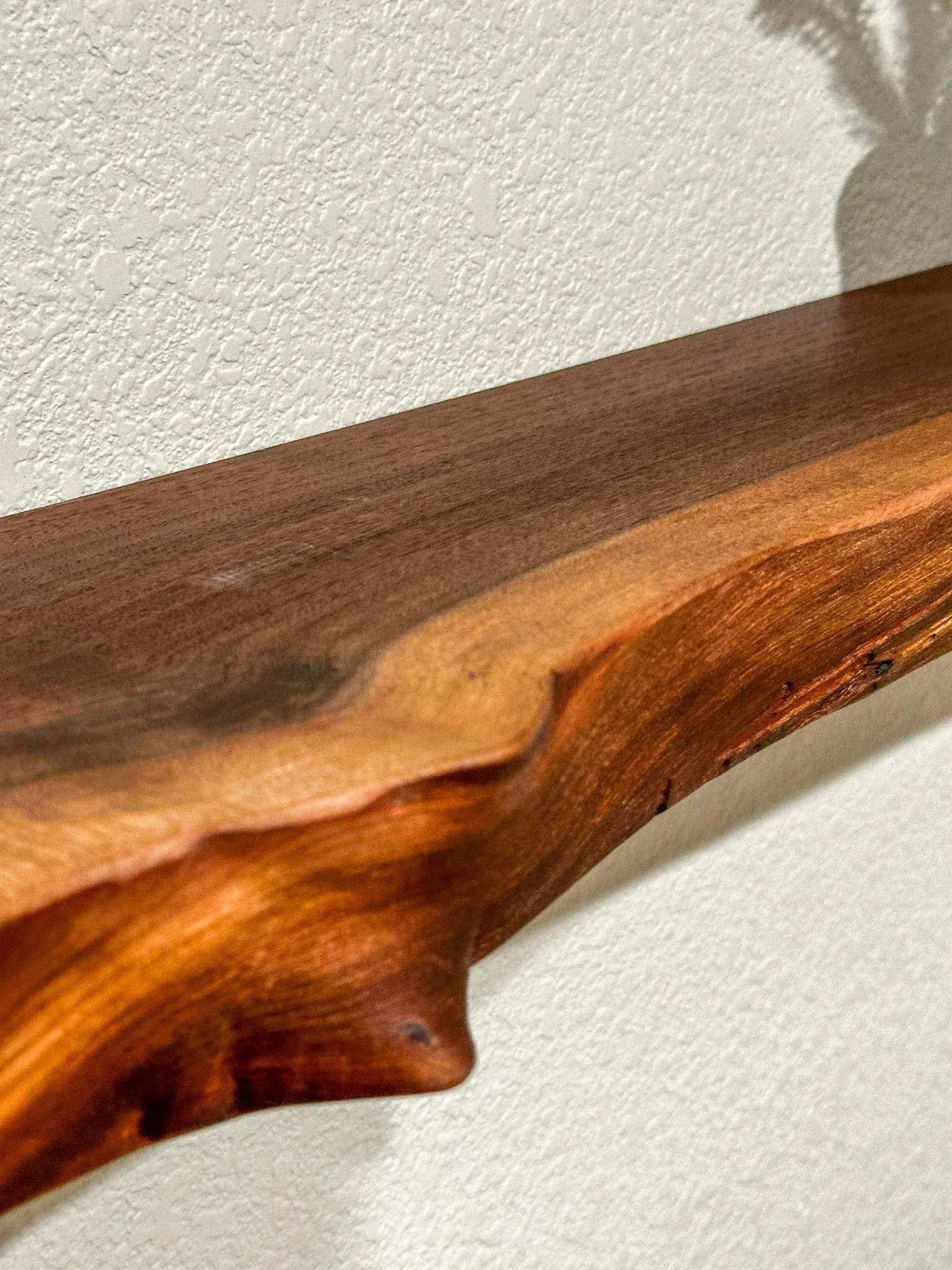 A wooden shelf is hanging on a white wall.