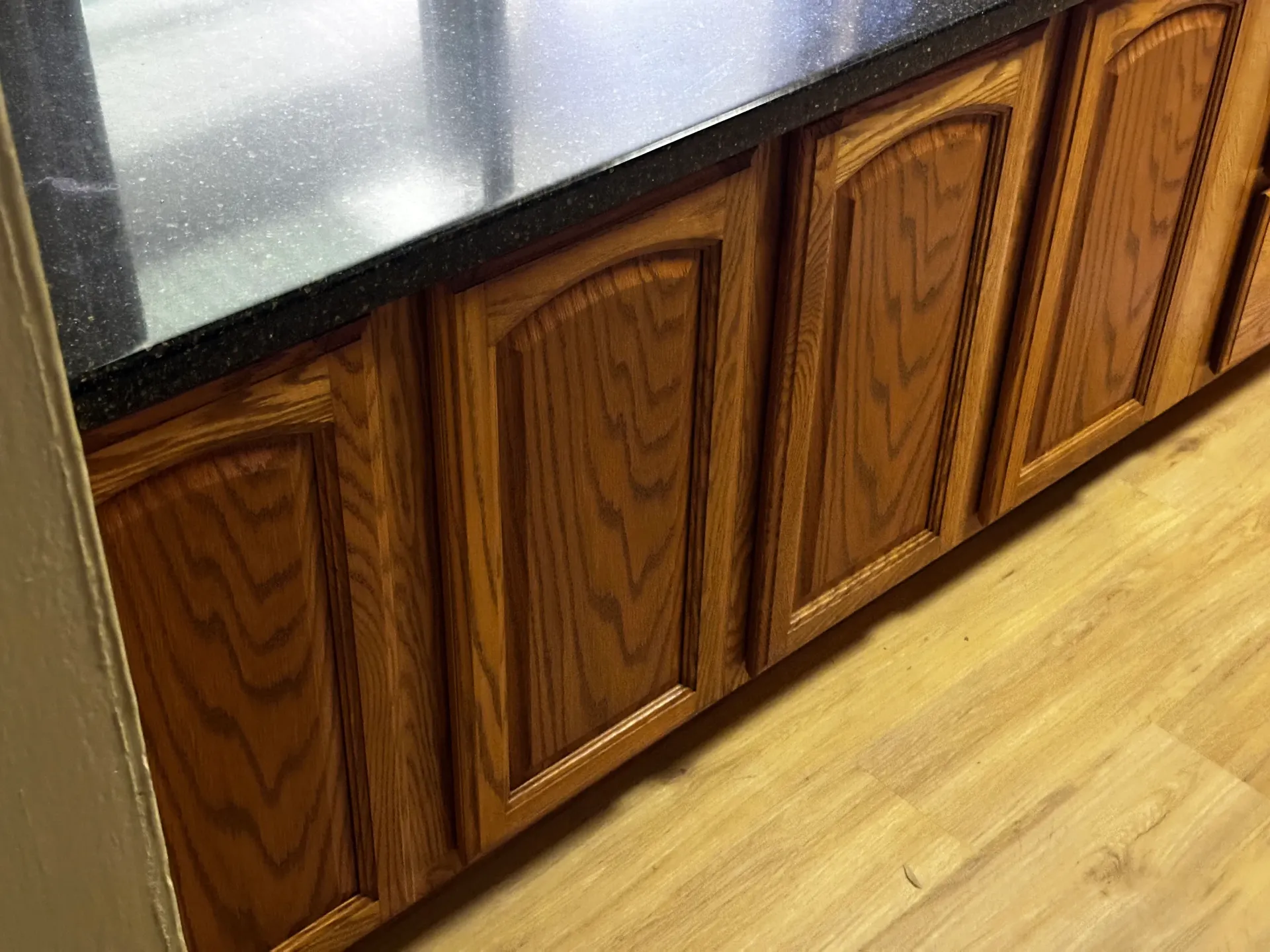 A kitchen with wooden cabinets and a black counter top