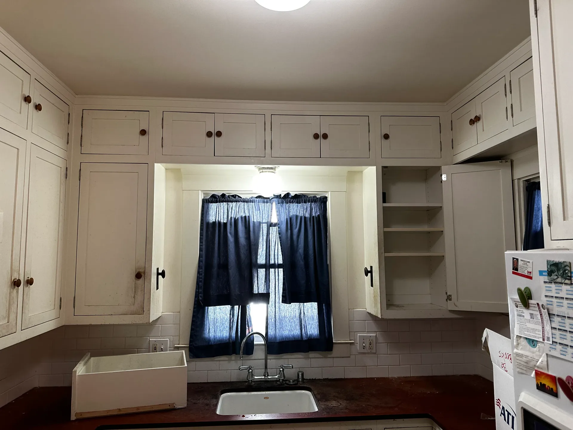 A kitchen with white cabinets a sink and a window