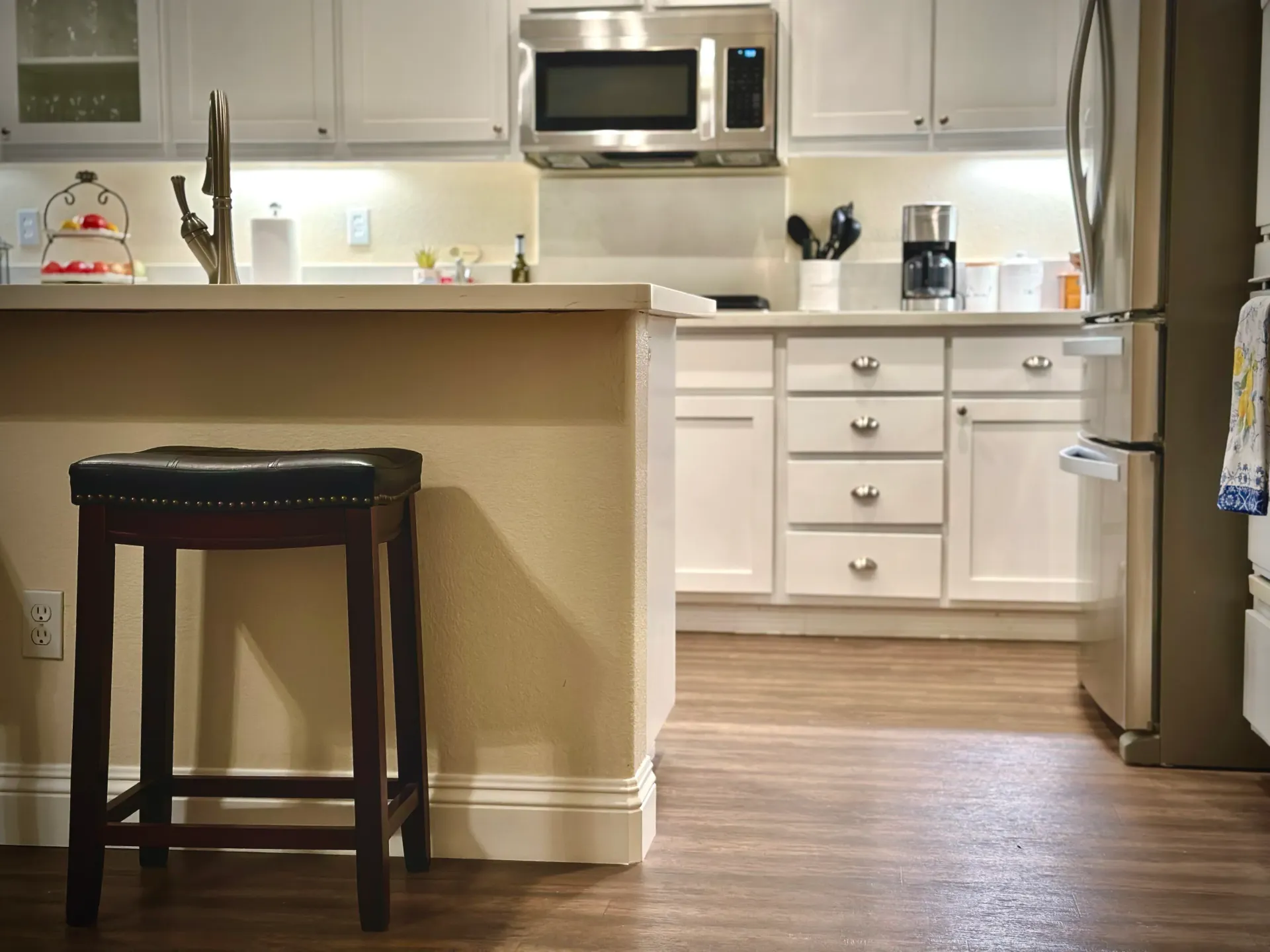 A kitchen with white cabinets and a stainless steel refrigerator