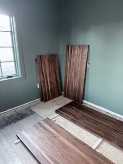 Partially finished room with wood flooring planks laid out on the floor and leaning against teal walls