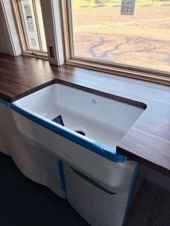 Built-in bench seat by a window with a white cushion and blue masking tape in a room under renovation