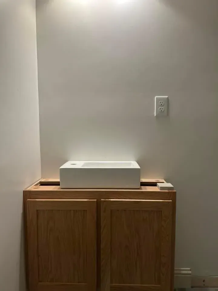 A bathroom sink is sitting on top of a wooden cabinet.