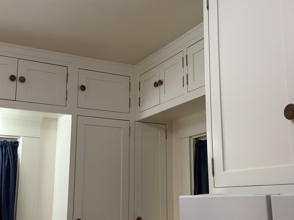 A kitchen with white cabinets and brown knobs
