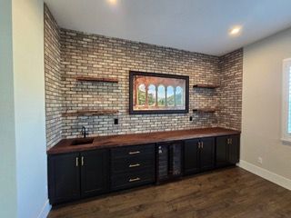Built-in black cabinets and wood countertop against a brick accent wall in a bright room