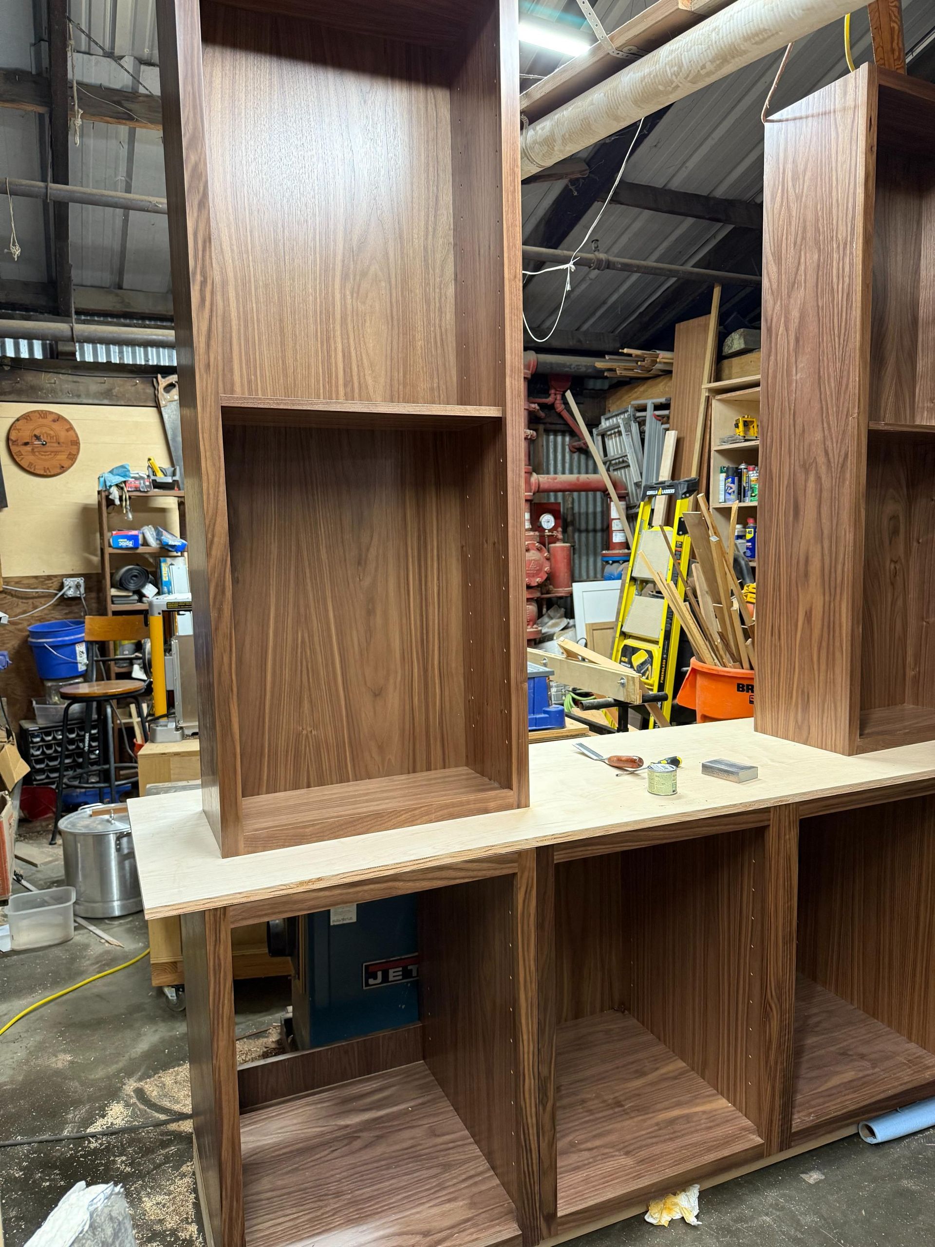 Solid wood bookshelves under construction in a workshop. The shelves are various heights with open compartments.