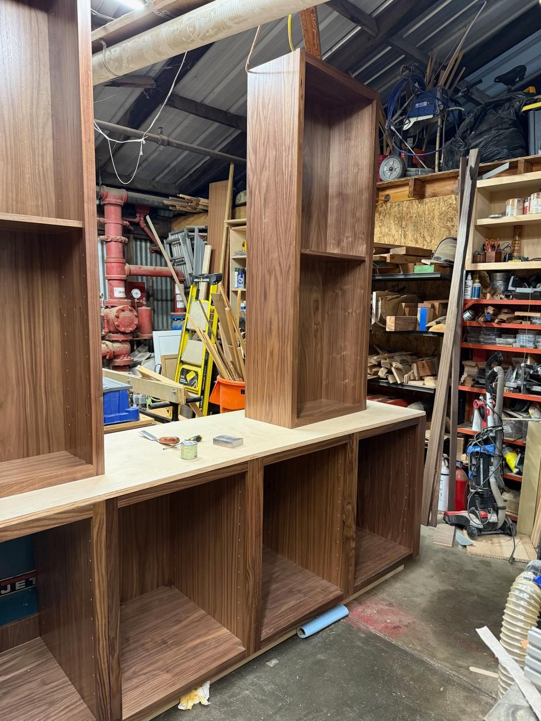 Solid wood bookshelves in a workshop, with open compartments and a taller central unit.