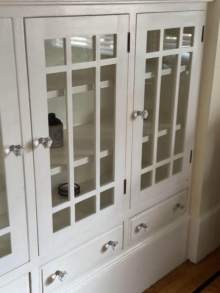 A white cabinet with glass doors and drawers