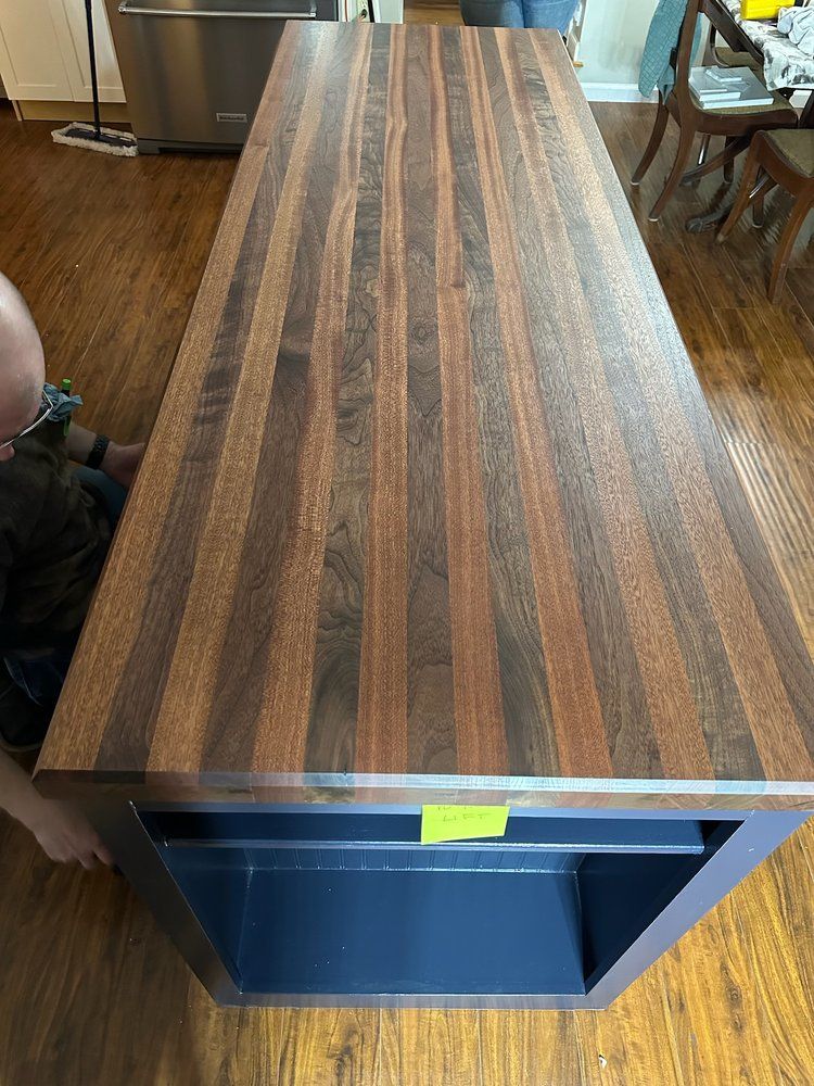 A wooden table is sitting on a wooden floor in a kitchen.