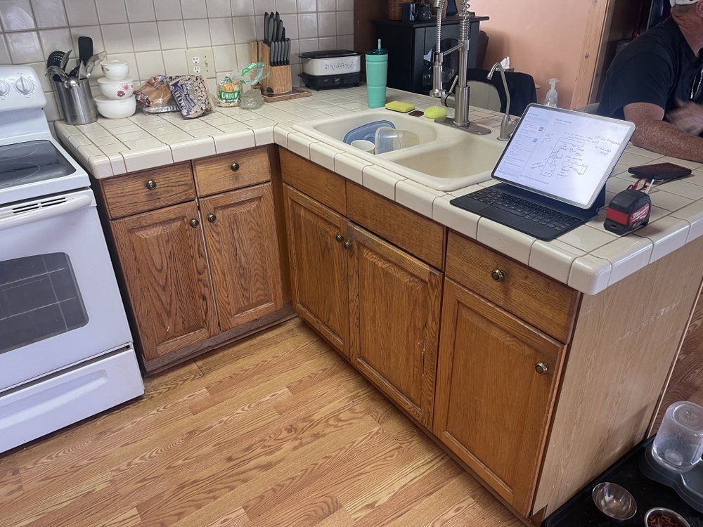 A kitchen with wooden cabinets and a laptop on the counter.