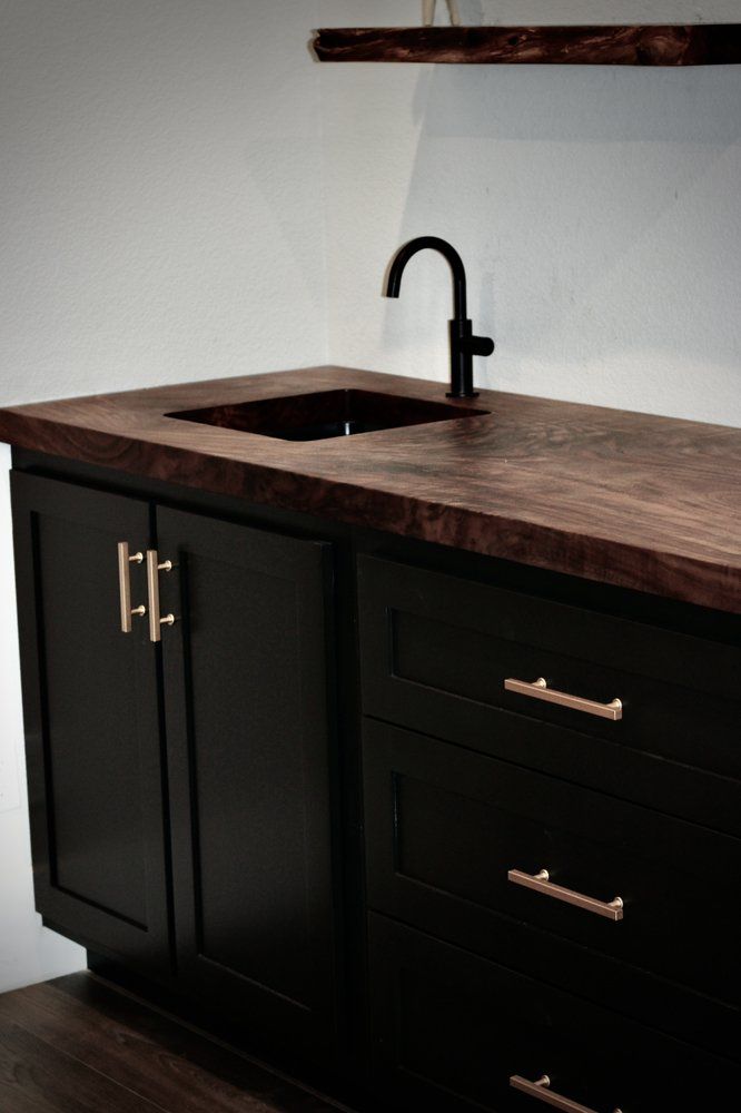 A kitchen with black cabinets and a sink
