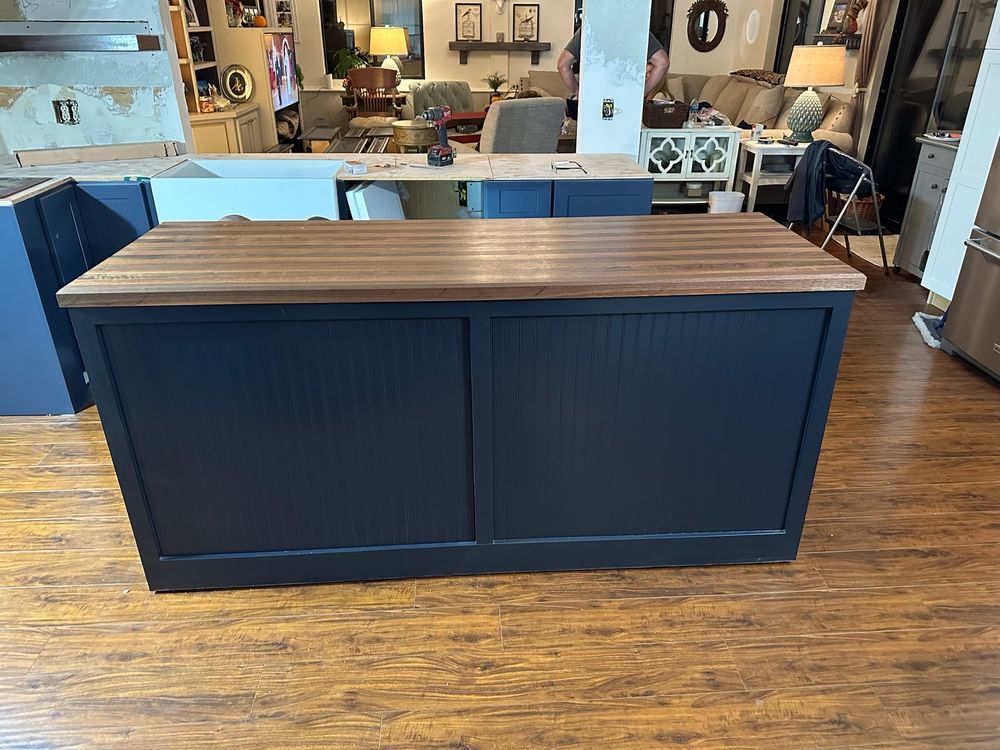A kitchen island with a wooden top is in the middle of a kitchen.