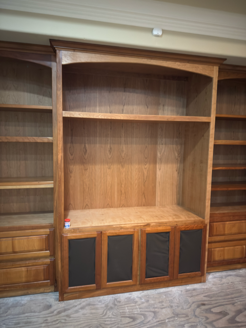 Built-in wooden bookshelf and cabinet with empty shelves and black cabinet doors