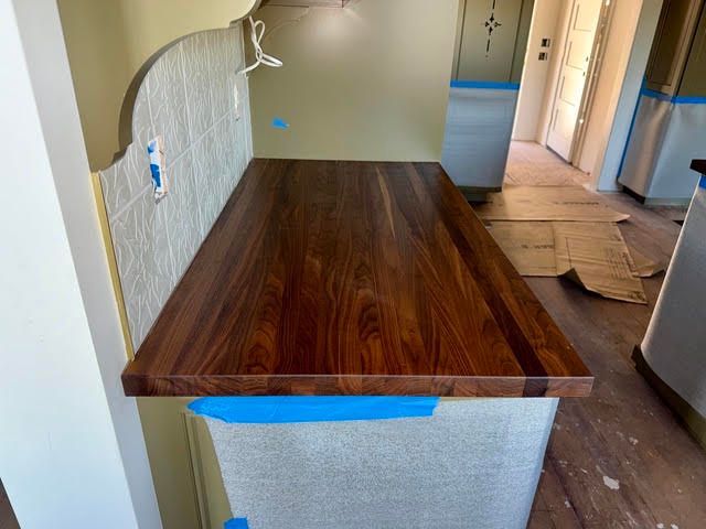 Kitchen countertop with dark wood finish and blue painter’s tape during renovation.