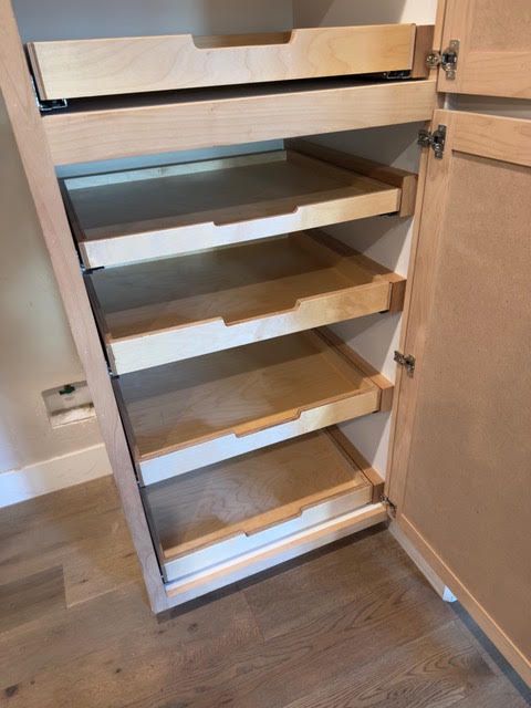 Open kitchen cabinet with pull-out wooden shelves and white drawer fronts