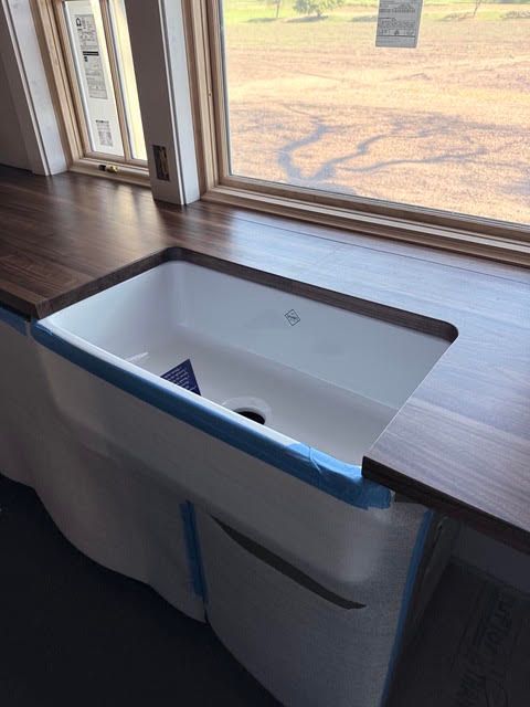 Wooden cabinet with an open white appliance built into a window-side countertop.