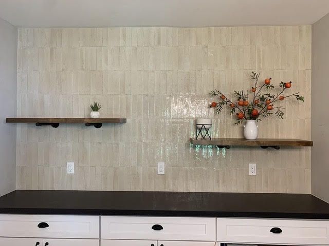 Empty built-in shelves with vases and decor above white drawers in a beige room