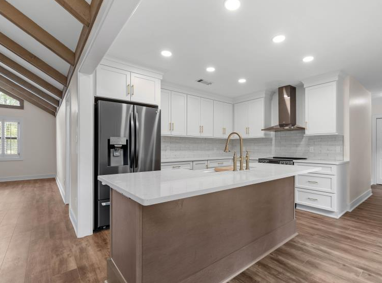 A kitchen with white cabinets , stainless steel appliances and a large island.