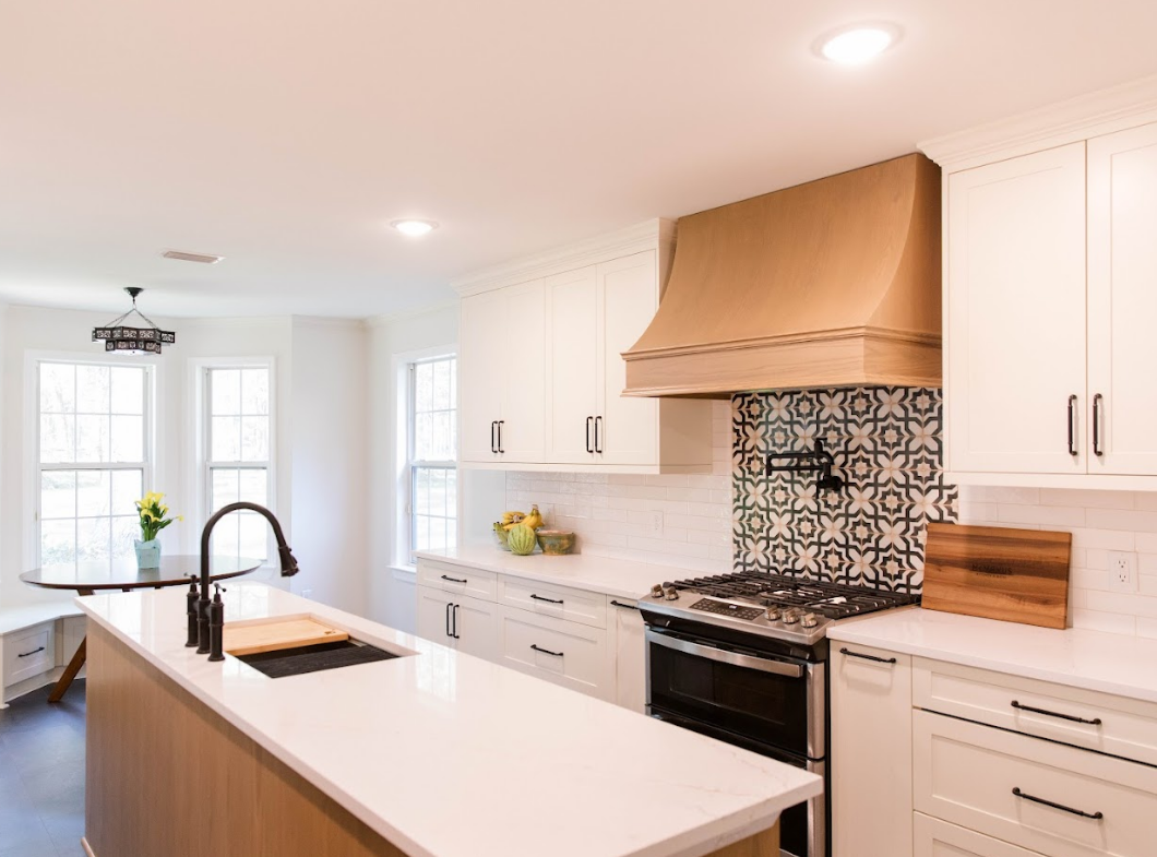 A kitchen with white cabinets , a stove , a sink , and a hood.
