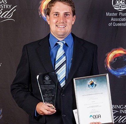 Justin Giles holding a trophy and award to honour the success of the 2015 MPAQ Best Commercial & Industrial Gas installation the year.