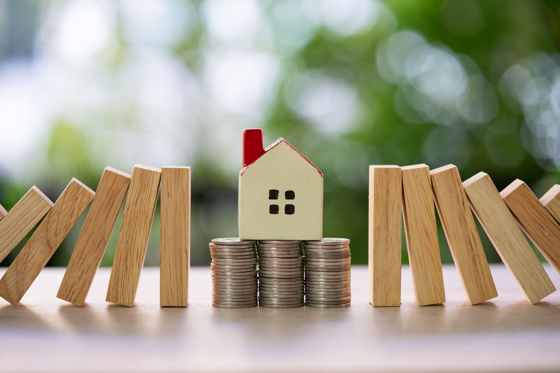 Cropped view of an insurance agent forming a home with their hands above a home insurance agreement.