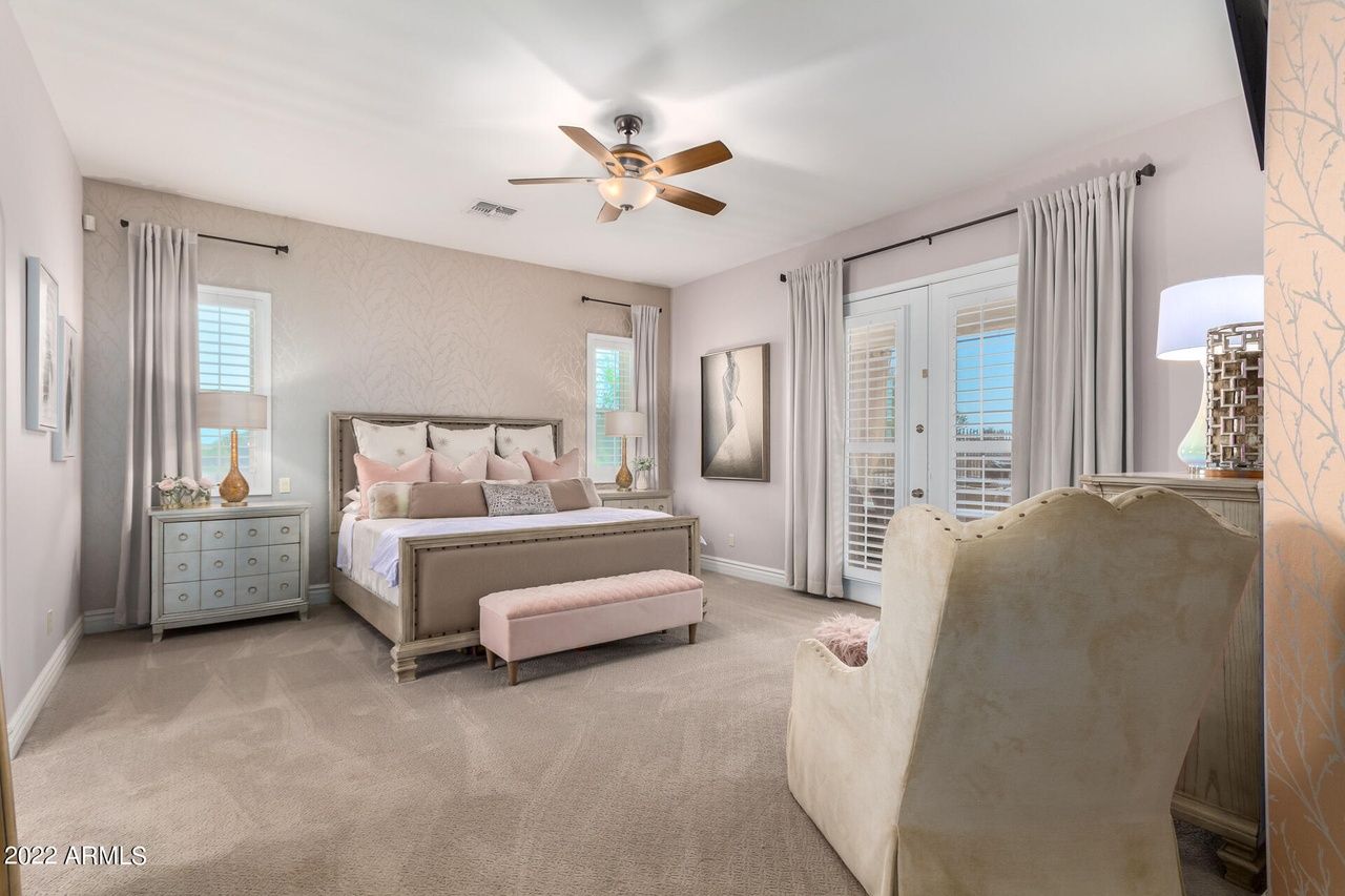 Bedroom with large bed, blush tones, and French doors leading to a balcony.