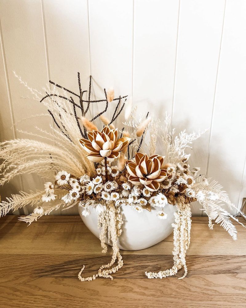 A Vase Filled With Dried Flowers is Sitting on a Wooden Table — Suncoast Flowers in Buderim, QLD
