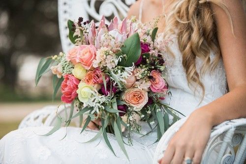 A Bride in a White Dress is Sitting in a Chair Holding a Bouquet of Flowers — Suncoast Flowers in Birtinya, QLD