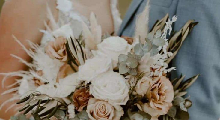 A Bride and Groom Are Holding a Bouquet of Flowers — Suncoast Flowers in Birtinya, QLD