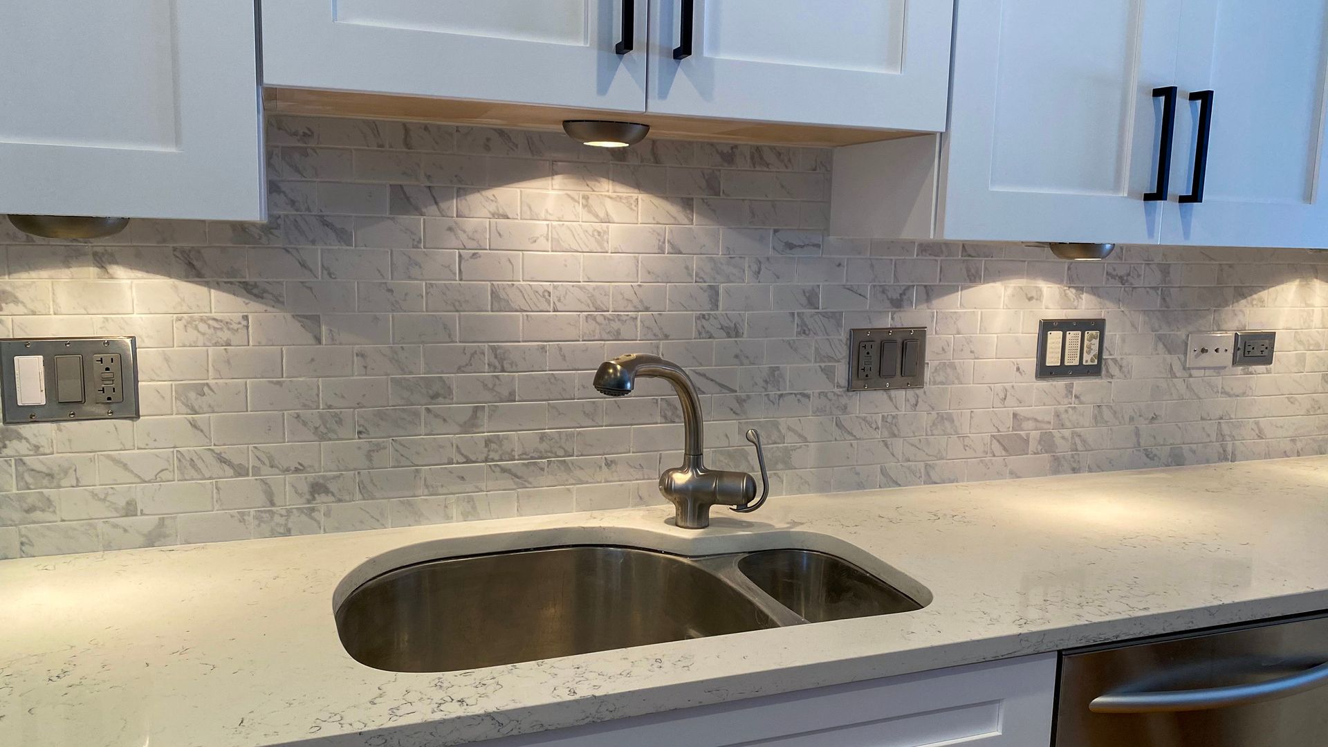 Modern kitchen countertop with stainless steel sink and white cabinets.
