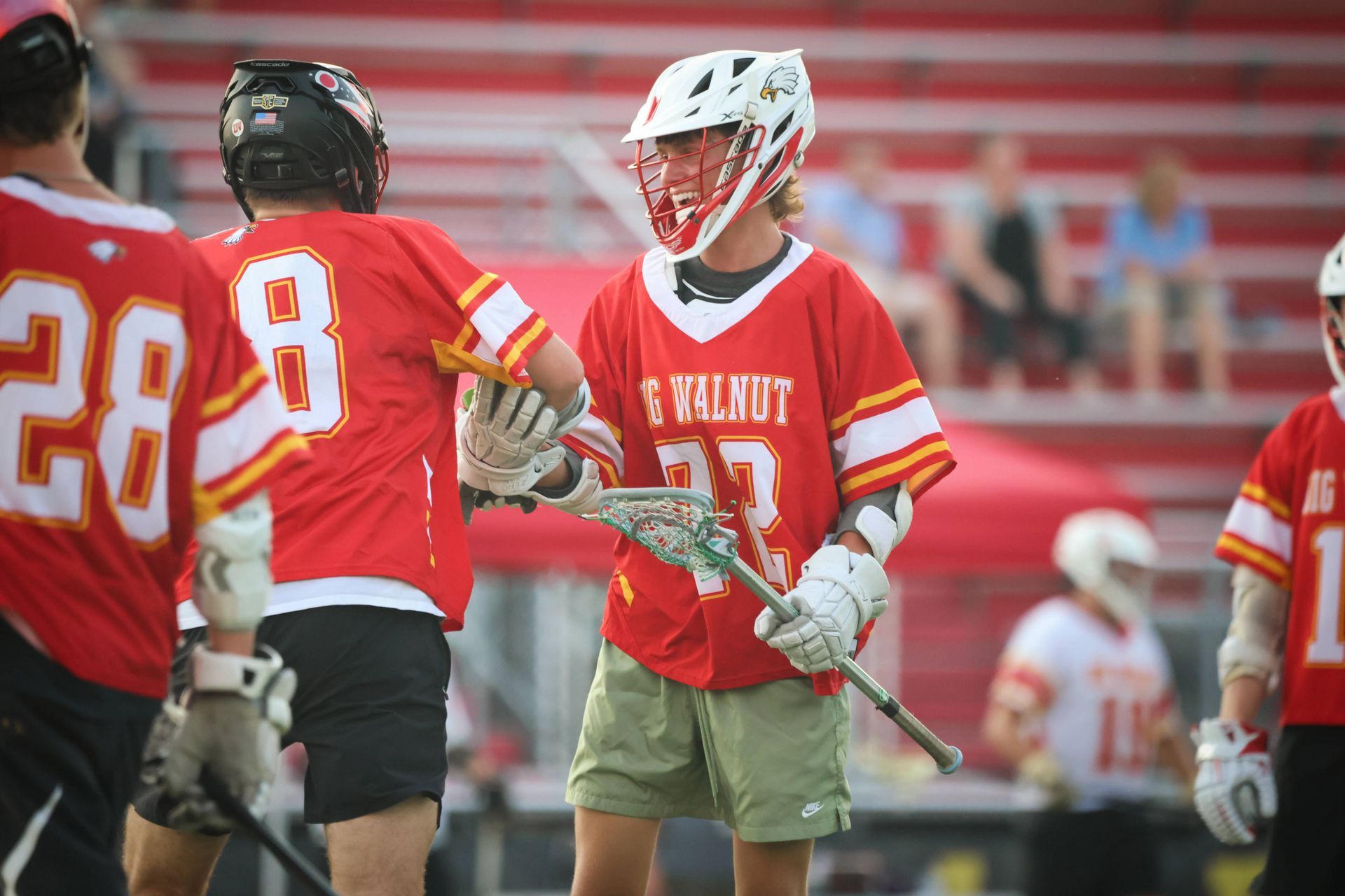 Lacrosse players in red uniforms standing on the field during a game, holding sticks.