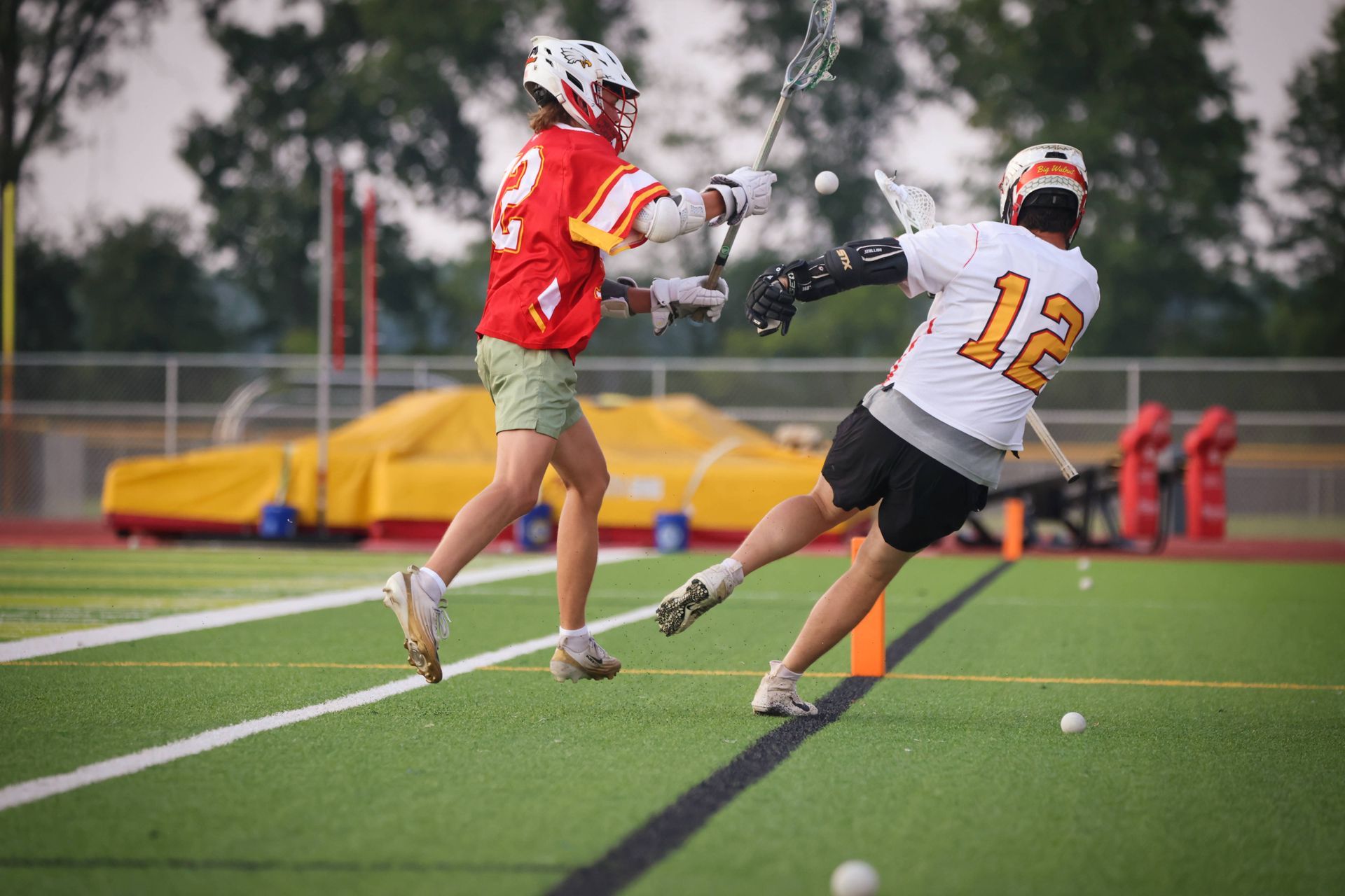 Two lacrosse players battling for the ball on a turf field during play