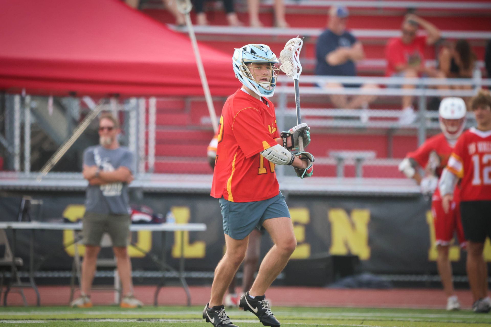 Lacrosse player in red jersey holding a stick on the field during a game