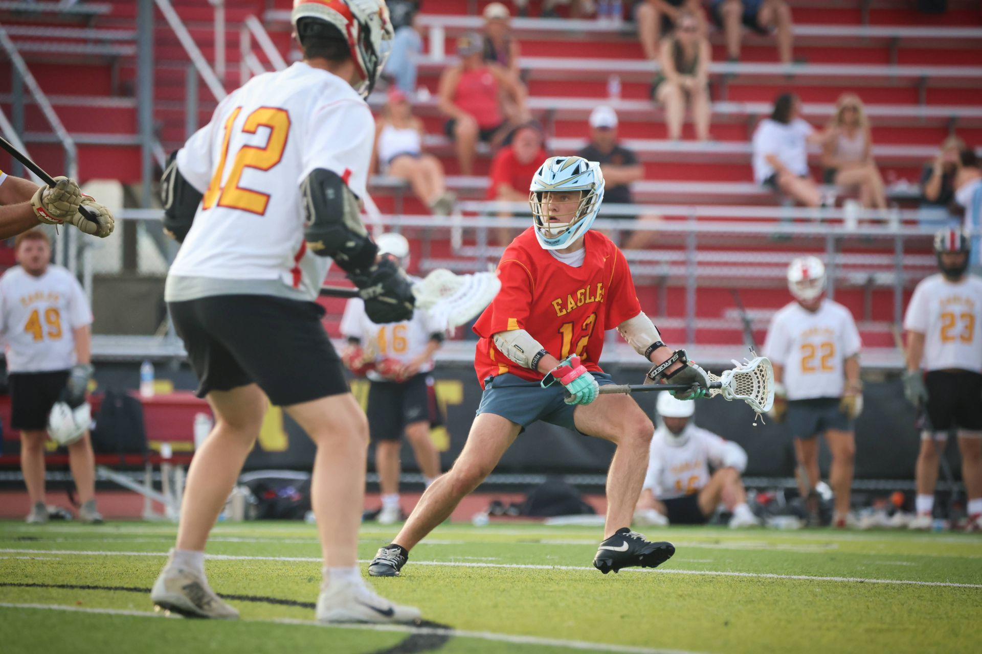 Lacrosse players in red and white battle on a field, with a red player cradling the ball.