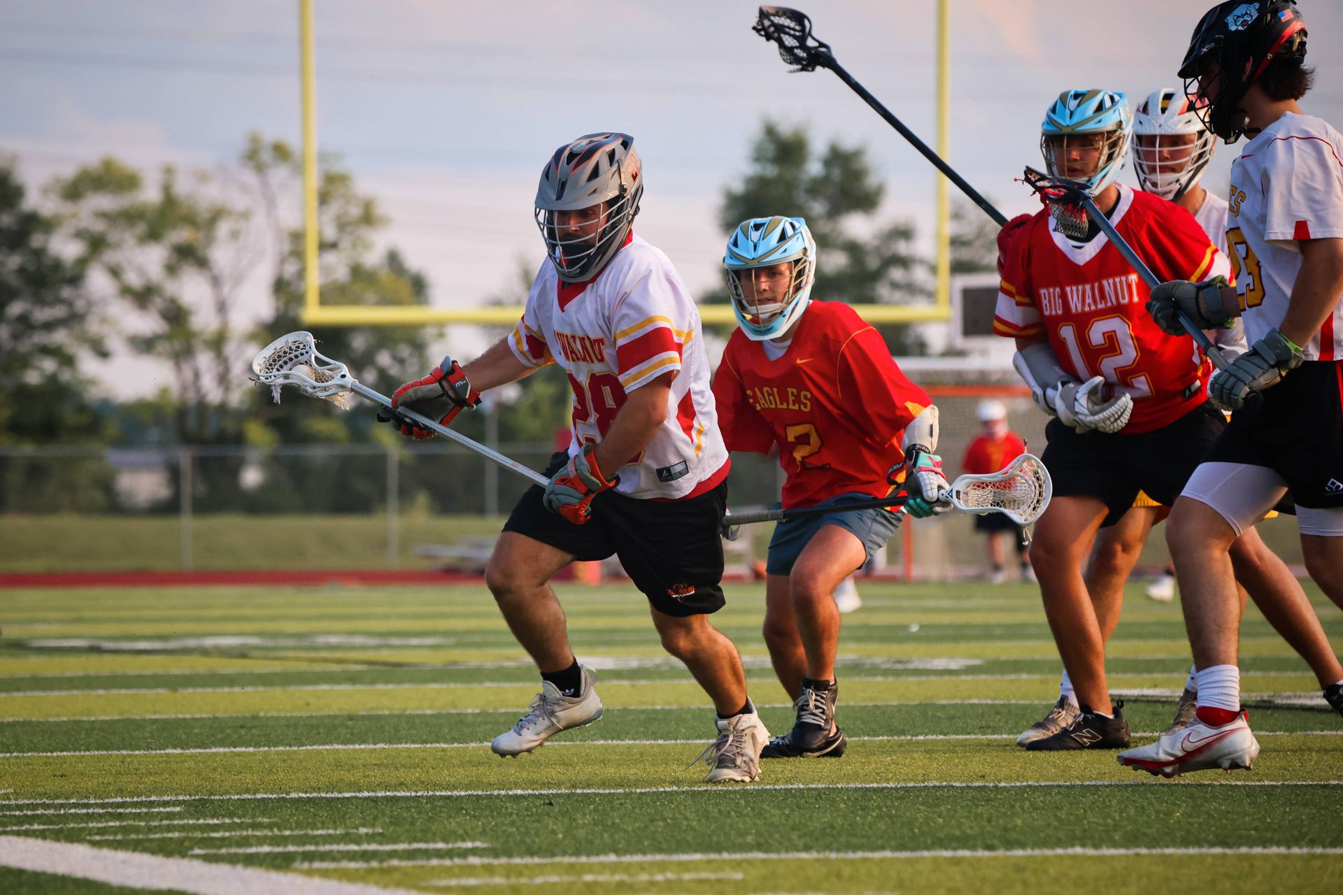 :acrosse players in red and white uniforms compete on a field during practice or a game
