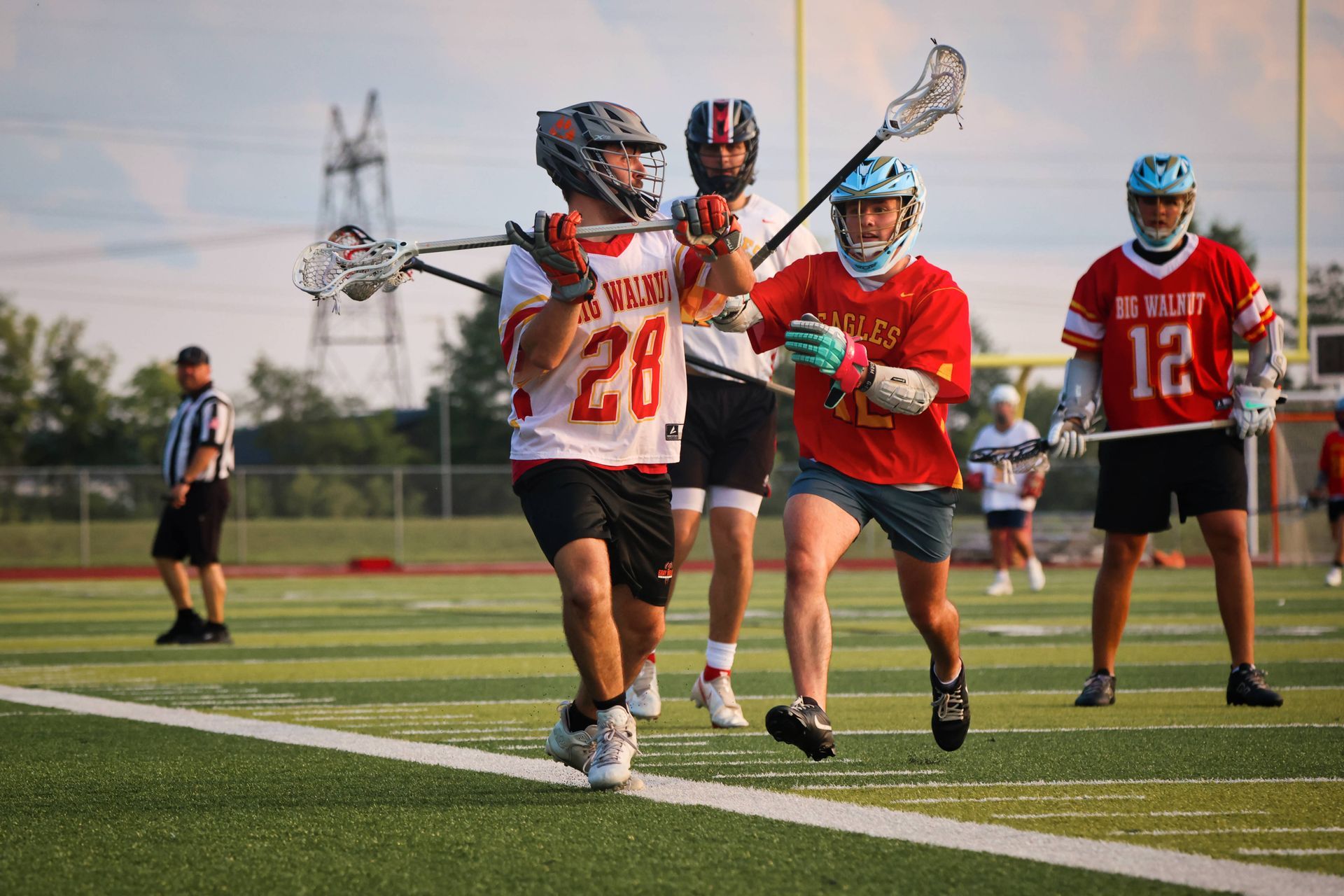 Lacrosse players in red and white uniforms running on a field during a game