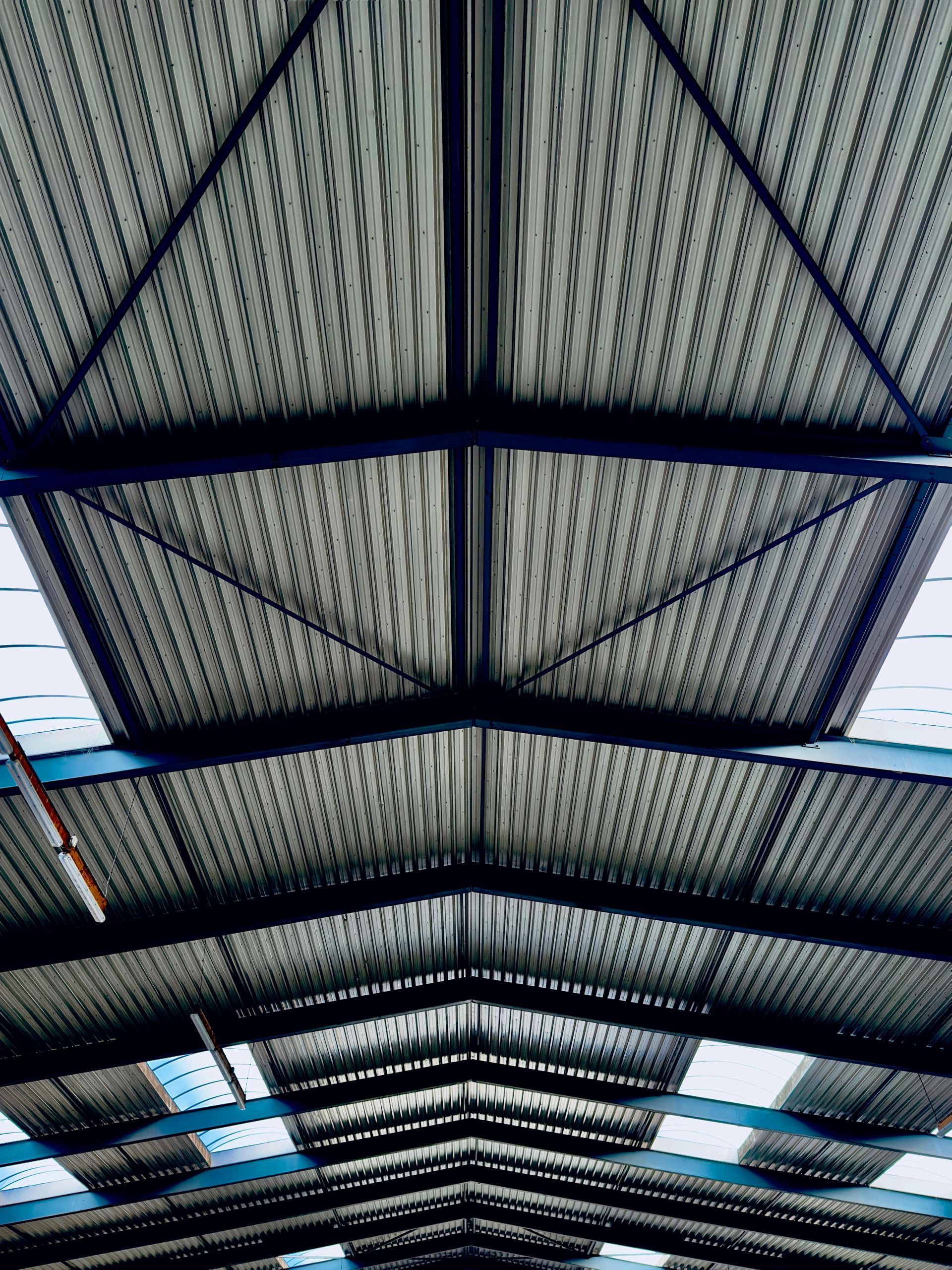 Looking upwards at a metal building roof with supporting beams.