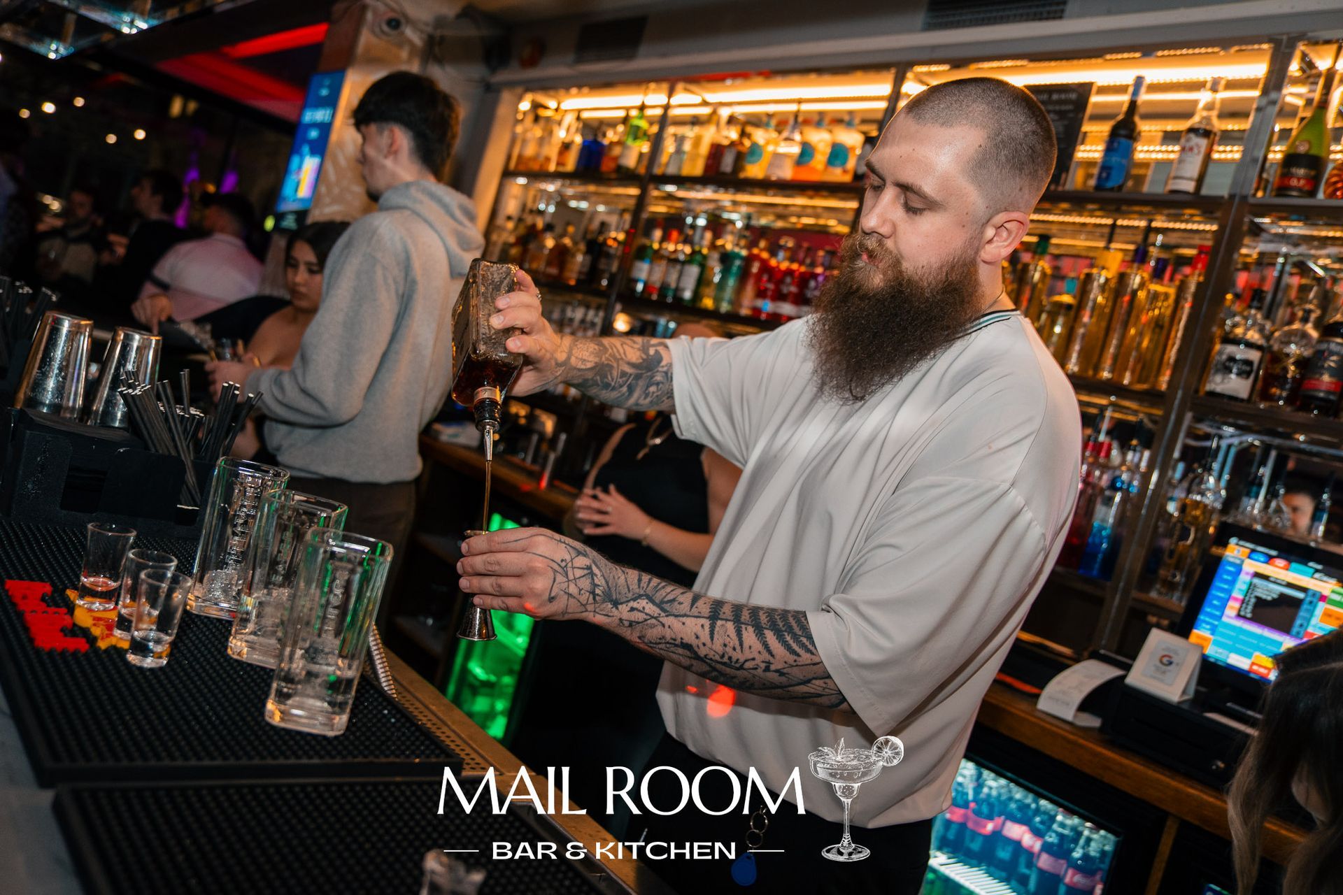 A man with a beard is making a drink in a bar.
