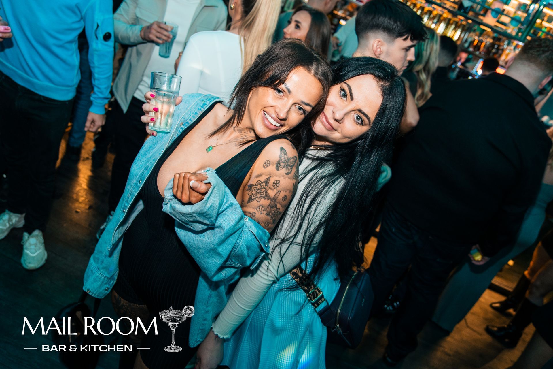 Two women are posing for a picture in a crowded room.