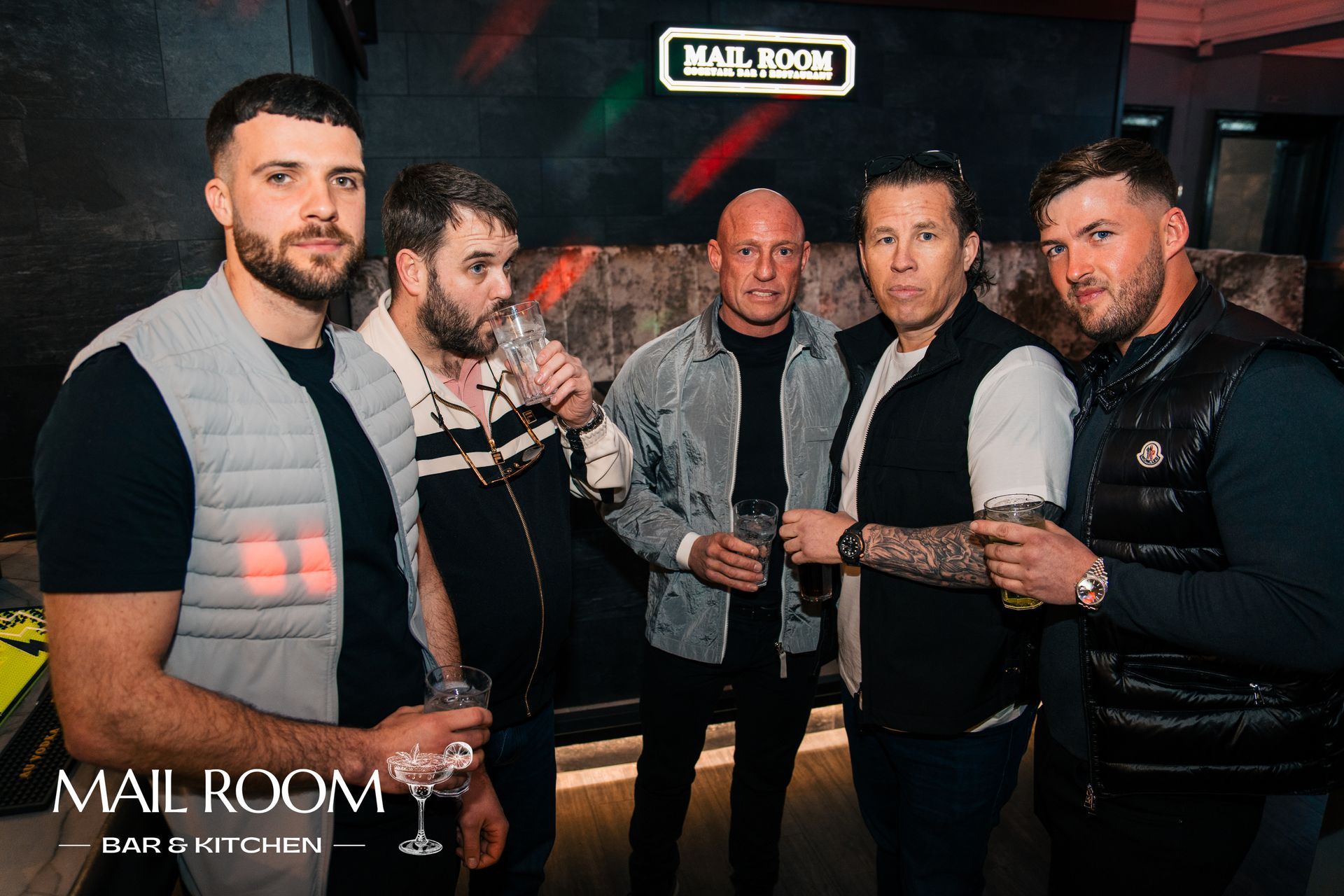 A group of men are posing for a picture in a club.