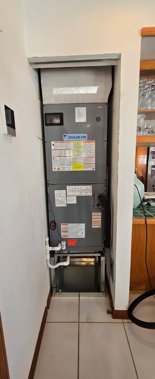 Open electrical panel in a wall recess, with labels and wiring visible in a tiled indoor space