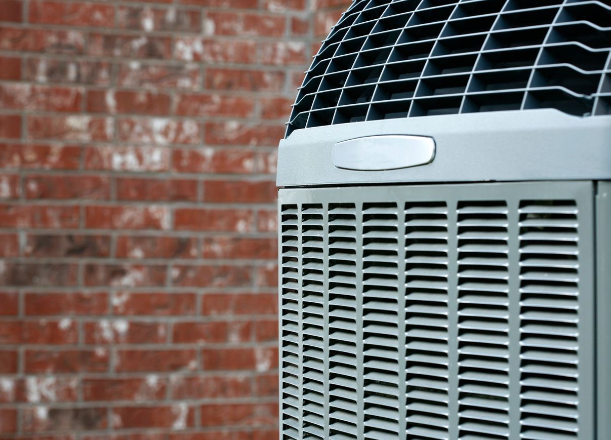 Outdoor air conditioning unit beside a red brick wall